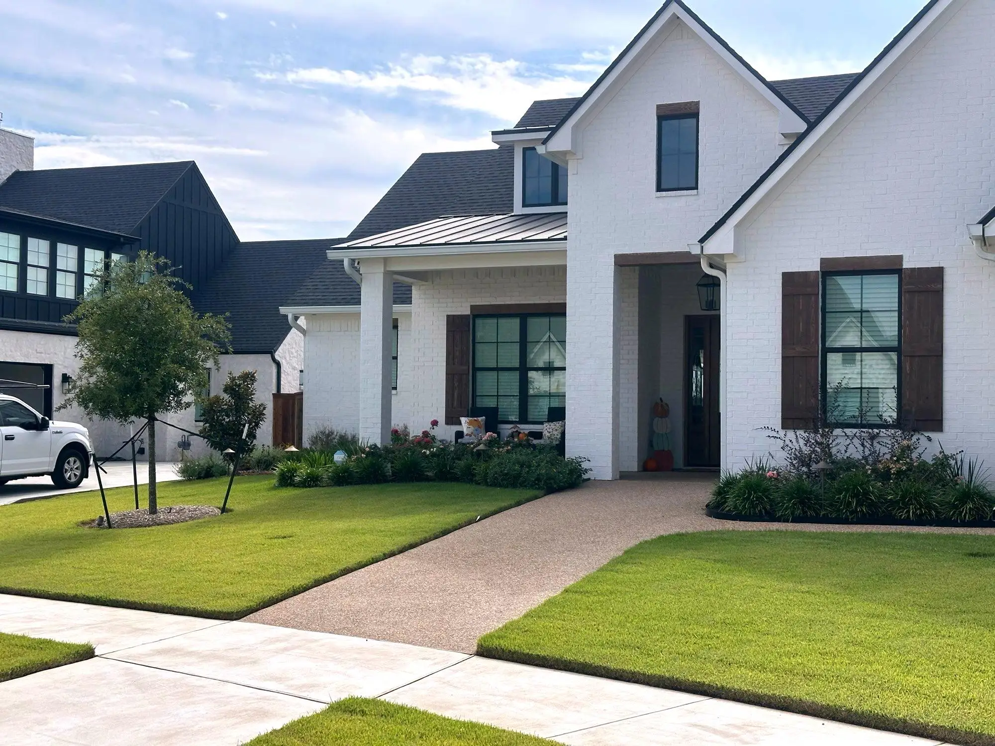 A Central Texas front yard maintained by H&M: manicured turf, layered beds, and a stone walkway.